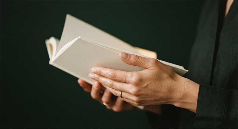 Hands holding an open book, softly out of focus