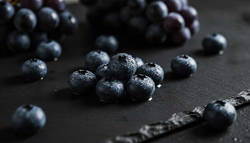 Fresh blueberries and dark grapes on wet slate