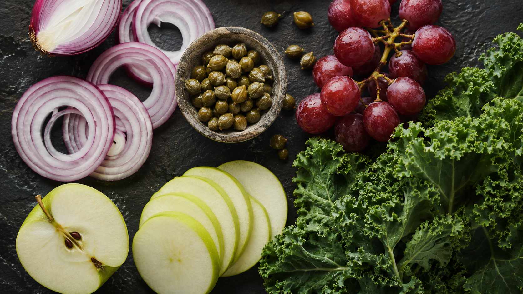 Quercetin-rich foods - red onions, apples, capers, red grapes on dark slate